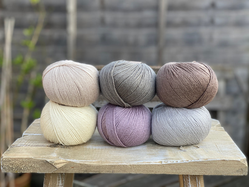 Six balls of yarn in soft neutrals including pale purple