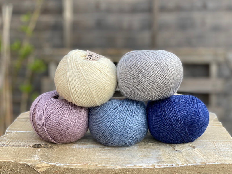Five balls of yarn in shades of blue and purple
