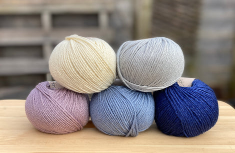 Five balls of yarn in shades of blue and purple