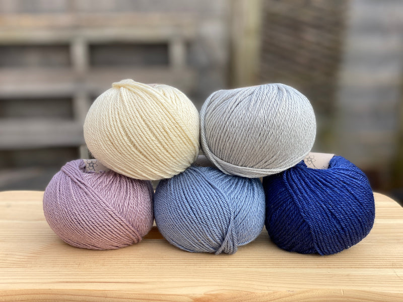 Five balls of yarn in shades of blue and purple