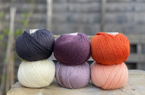 Six balls of yarn in purple, orange, black and white