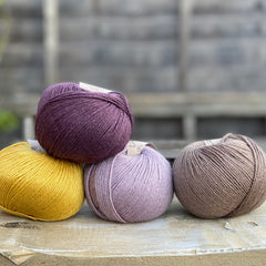 Four balls of yarn. Colours are yellow, dark purple, pale purple and brown