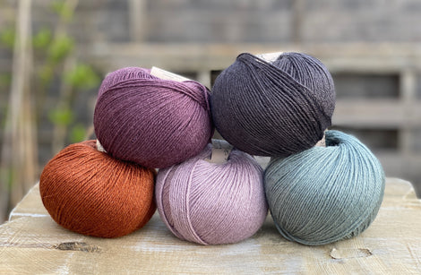 Five balls of Milburn 4ply in purple, grey, green and rust.