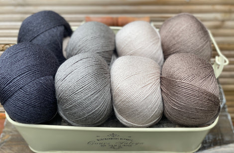 Eight balls of yarn in four pairs. From left to right the colourways are black, grey, beige and brown