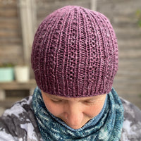 An image of Victoria's purple hat. The hat has textured stitches running up the height of the hat and gathering at the crown