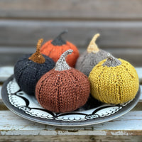 Four knitted pumpkins on a plate