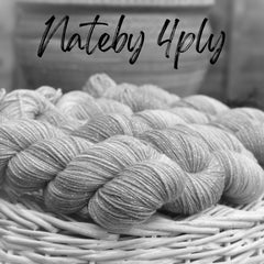 A black and white image of four skeins of yarn resting on a wicker basket. The yarn appears lightly variegated and has a thread of silver sparkle running throughout it. Nateby 4ply is written across the top of the image in black text