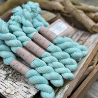 A pile of mini skeins of light turquoise yarn