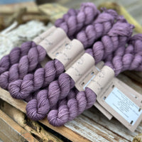 A pile of mini skeins of dark purple yarn
