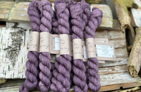 A pile of mini skeins of dark purple yarn