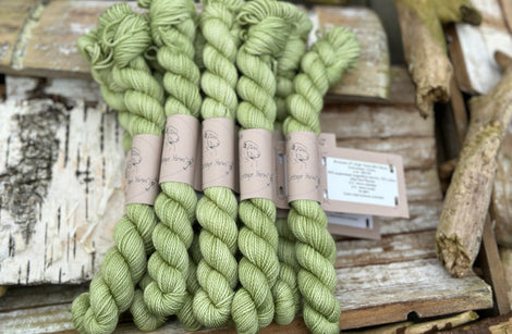 A pile of mini skeins of green yarn