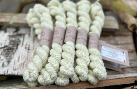 A pile of mini skeins of pale greeny yellow yarn