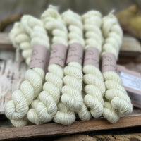 A pile of mini skeins of pale greeny yellow yarn