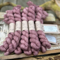 A pile of mini skeins of pinky purple yarn
