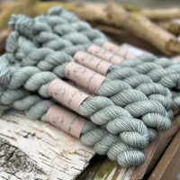 A pile of mini skeins of greenish grey yarn