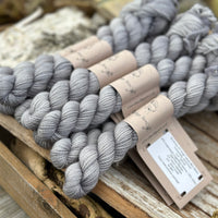 A pile of mini skeins of grey yarn