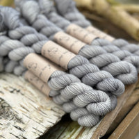 A pile of mini skeins of grey yarn
