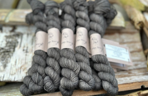 A pile of mini skeins of dark grey yarn