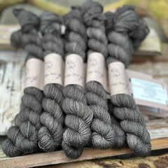 A pile of mini skeins of dark grey yarn