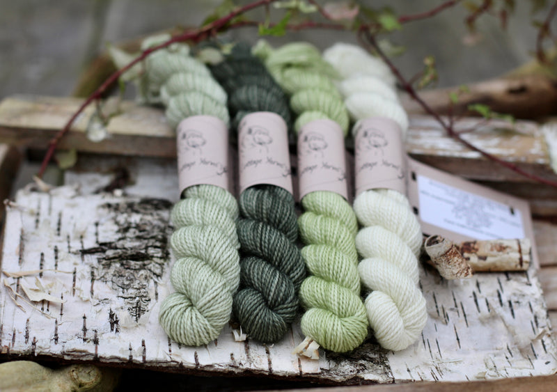 Four mini skeins of yarn in shades of green