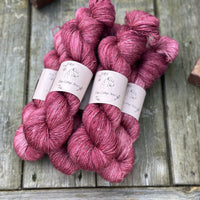 Five skeins of purpley-red yarn with white slubs running through them