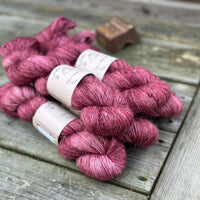 Five skeins of purpley-red yarn with white slubs running through them