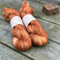 Two skeins of light orangey brown yarn with pale slubs running through them