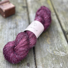 One skein of dark purple yarn with pale linen slubs running through it