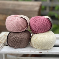Four balls of yarn in two piles of two balls. On the left is a pink ball and a brown ball. On the right is a deep pink ball and a cream ball