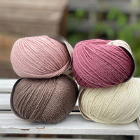 Four balls of yarn in two piles of two balls. On the left is a pink ball and a brown ball. On the right is a deep pink ball and a cream ball