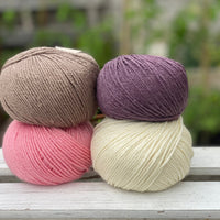 Four balls of yarn in two rows of two balls. There is a bright pink ball, a cream ball, a brown ball and a dark purple ball