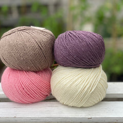 Four balls of yarn in two rows of two balls. There is a bright pink ball, a cream ball, a brown ball and a dark purple ball