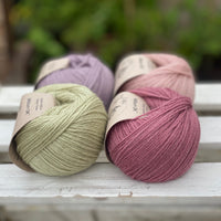 Four balls of yarn in two rows of two. There is a pale purple ball, a light pink ball, a light green ball and a dark pink ball.