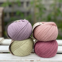 Four balls of yarn in two rows of two. There is a pale purple ball, a light pink ball, a light green ball and a dark pink ball.