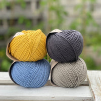 Four balls of yarn in two rows of two. There is a yellow ball, a dark grey ball, a blue ball and a grey ball.
