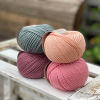 Four balls of yarn in two rows of two. There is a blue-green ball, a peachy orange ball, a dark pink ball and a bright pink ball.