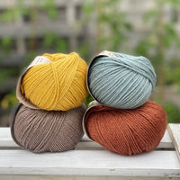 Four balls of yarn in two rows of two balls. There is a yellow ball, a brown ball, a blue-green ball and a reddish brown ball.