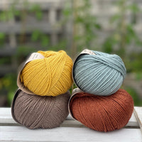 Four balls of yarn in two rows of two balls. There is a yellow ball, a brown ball, a blue-green ball and a reddish brown ball.