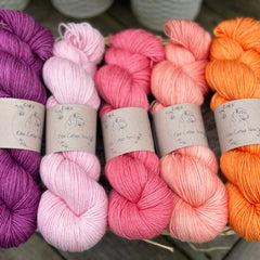 Five skeins of yarn in shades of pink, purple and orange