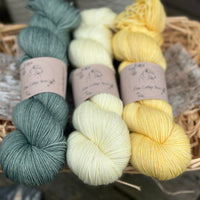 Three skeins of yarn in shades of green and yellow
