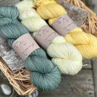 Three skeins of yarn in shades of green and yellow