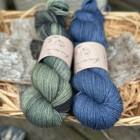 Two skeins of yarn - one variegated green skein and one dark blue skein