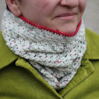 Victoria wearing a crochet cluster cowl in variegated cream, green and red yarn with a red edging. The yarn has silver sparkle running through it