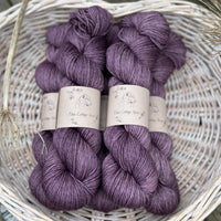 Five skeins of dark purple yarn in a white wicker basket
