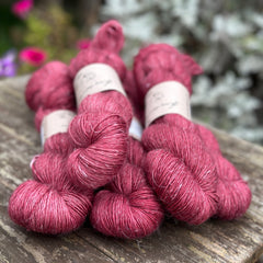 Five skeins of purpley red yarn with white flecks of linen running through it