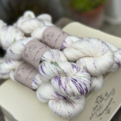 Five skeins of natural cream yarn with splashes of purple, green and brown