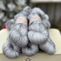 Five skeins of grey yarn with dark brown speckles