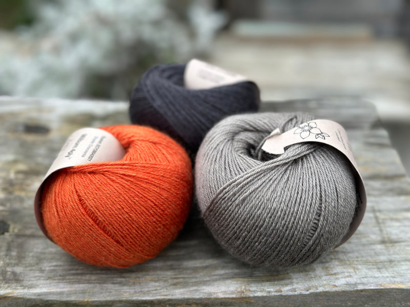 Three balls of yarn - one black, one orange and one grey