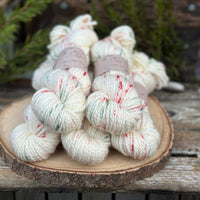 Five skeins of cream yarn with green and red speckles