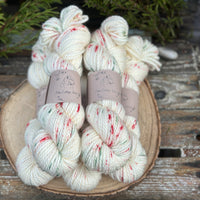 Five skeins of cream yarn with green and red speckles